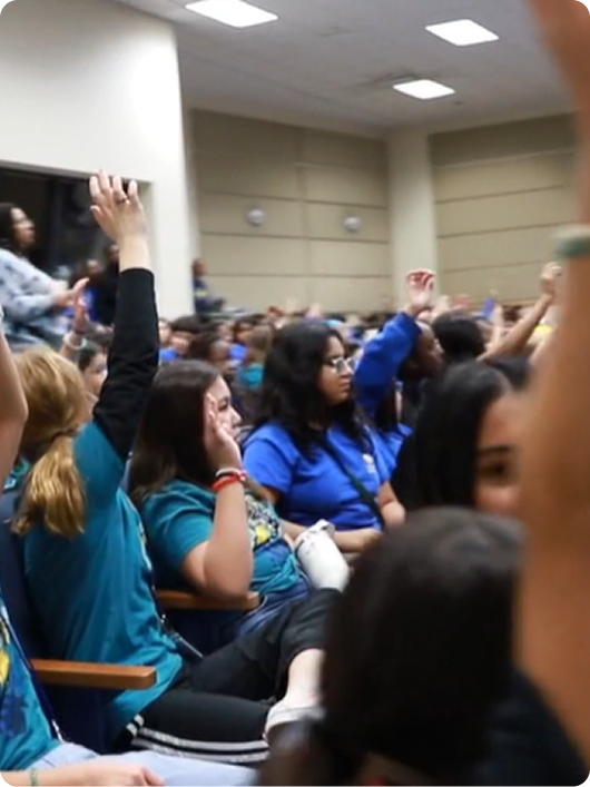 Students raising their hands in an auditorium during a BrainAbouts assembly